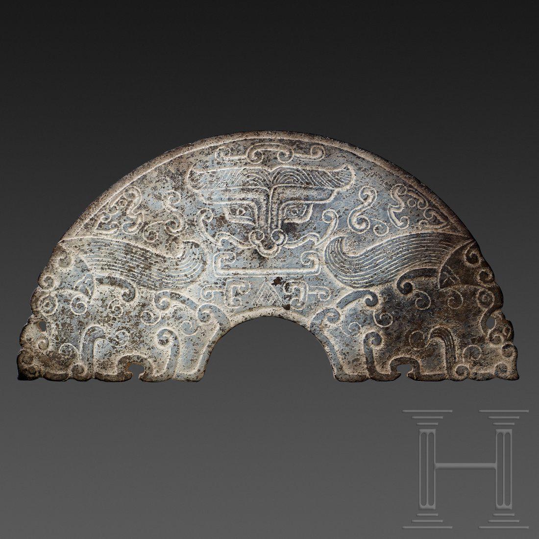 A half of a Chinese Bi-disc, circa 1900: In the center - on both sides - the mythical horned creature Tao-t'ieh, framed by cloud pattern ornamentation. Blackish nephrite with whitish calcination. Intact. Length 20.6 cm. In the style of the w