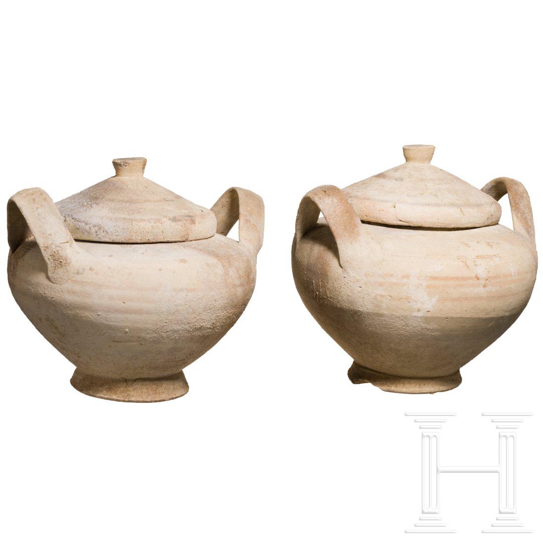 A pair of Daunian-Italian pots, 5th â€“ 4th century: Two pots. Each with lid. The lids broken and expertly glued. On one pot still remains of the decoration in the form of dark bands. One handle glued. Intact. Height 17 cm and 18 cm.Provenance: From a p