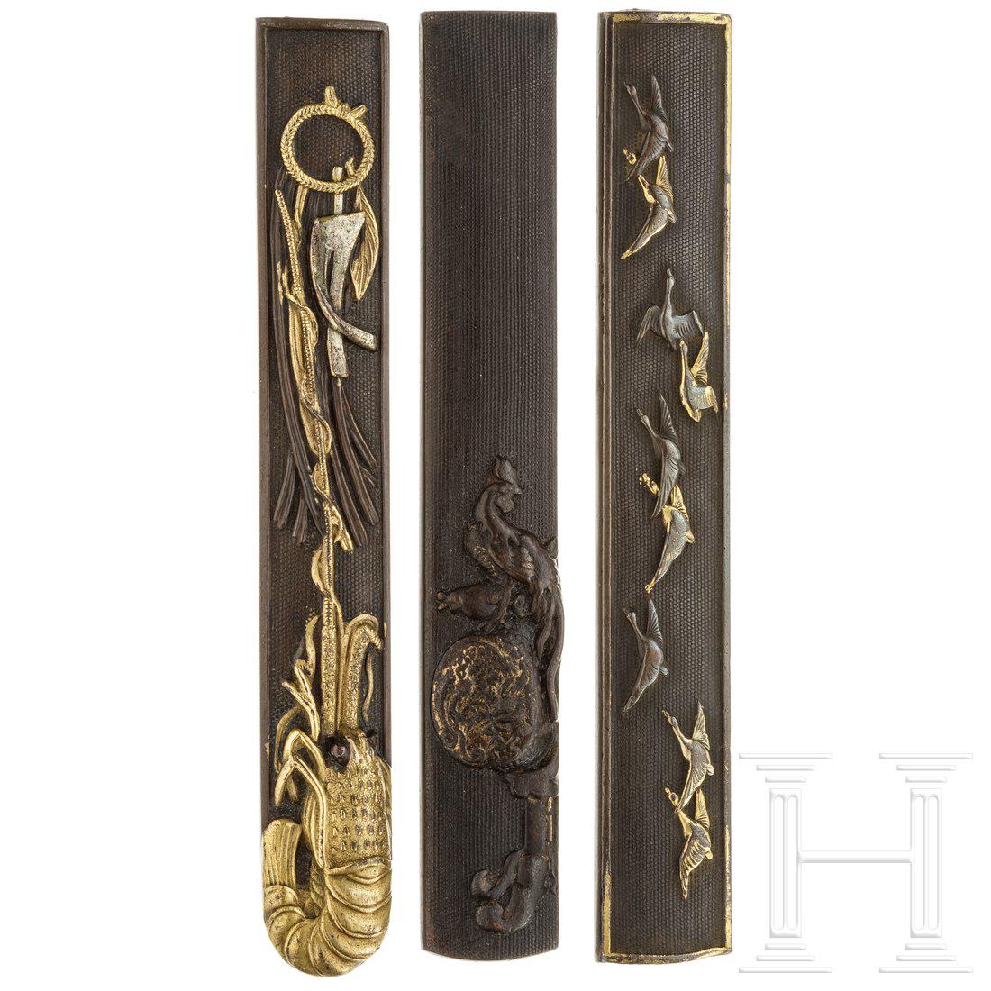 Three Japanese kozukas, circa 1800: Unterschiedliches Dekor aus einem Hahn auf einer Trommel, einem Feldzeichen sowie fliegenden WildgÃ¤nsen. Jeweils auf Shahudonanako, Niguromenanako und weiterem Niguromenanako. Teilweise vergoldet u