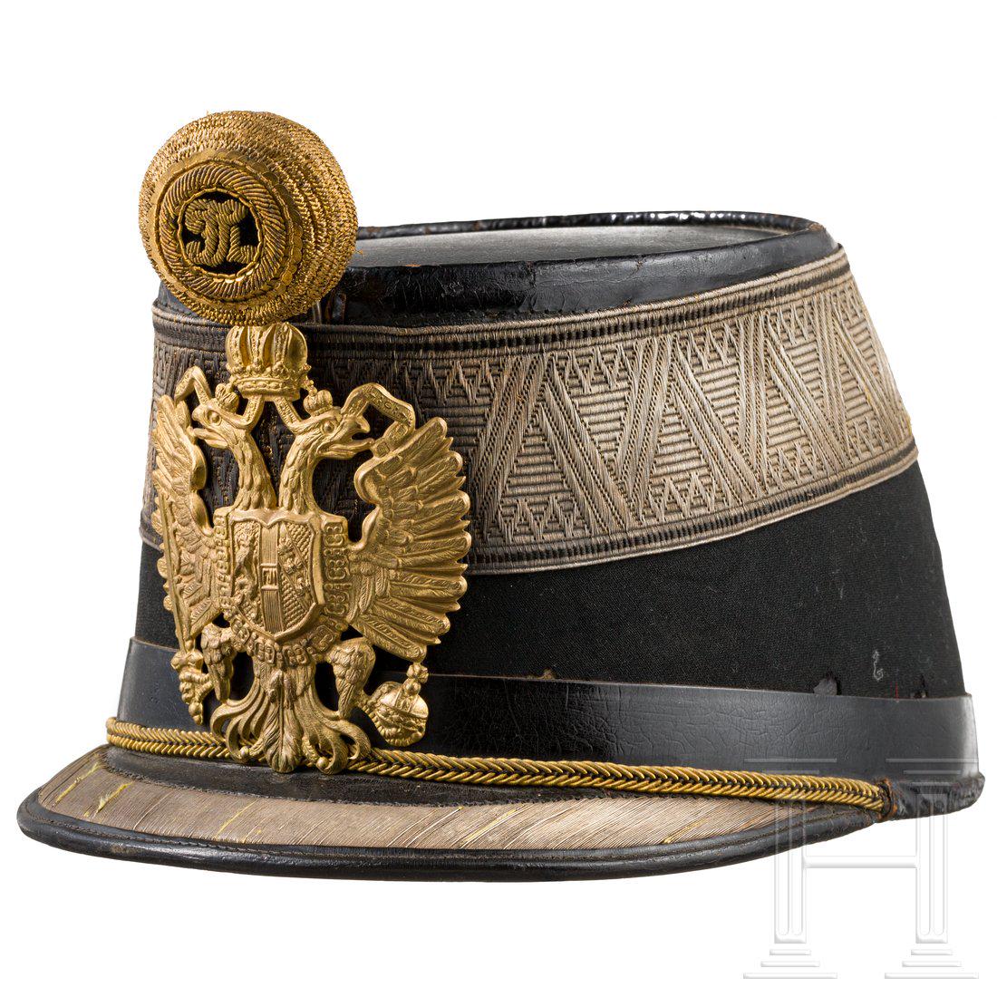 A shako for subalternofficers of the k. u. k. infantry: Korpus mit schwarzem Tuch bezogen (kleine Fehlstellen), Lederdeckel (berieben), umlaufende silbervergoldete Distinktionsborte (gedunkelt), lederner Schirm, daran silbergoldene Stickerei (gedunkelt). V