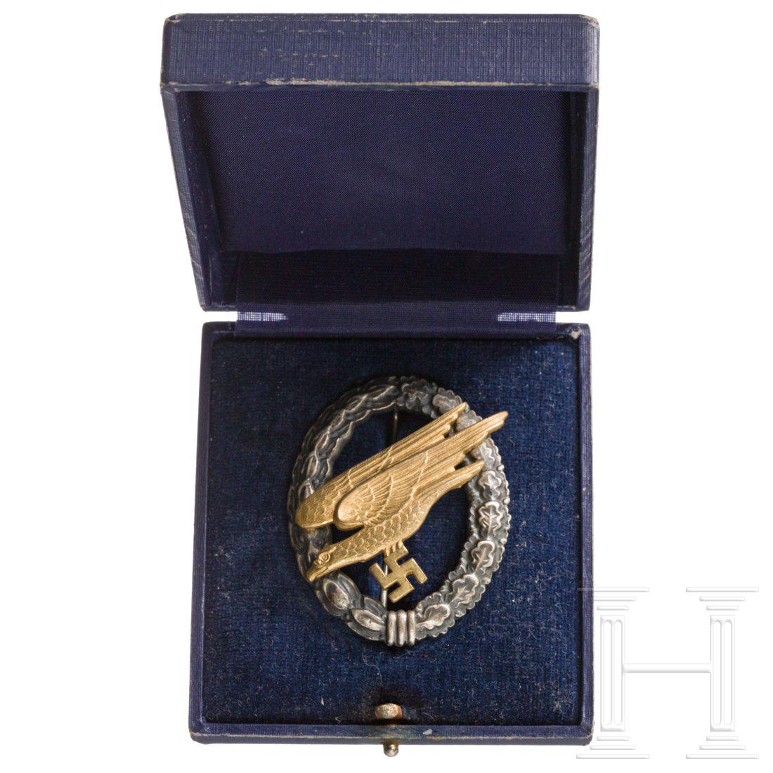 A Luftwaffe paratrooper's badge made by Assmann: FrÃ¼he BuntmetallausfÃ¼hrung, der dunkel patinierte Kranz mit rs. vertikaler Drahtnadel an Rollenscharnier, der vernietete, vergoldete Adler mit rs. punziertem Herstellerlogo. Dazu ein neuzeitlich