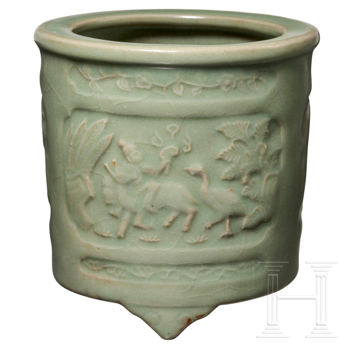 A Chinese Longquan censer with figural relief design,: Cylindrical vessel on three short feet with celadon glaze. On the outside three fields with engraved mythological scene. Intact. Height 12 cm. Diameter 12.5 cm. Provenance: From a South German private