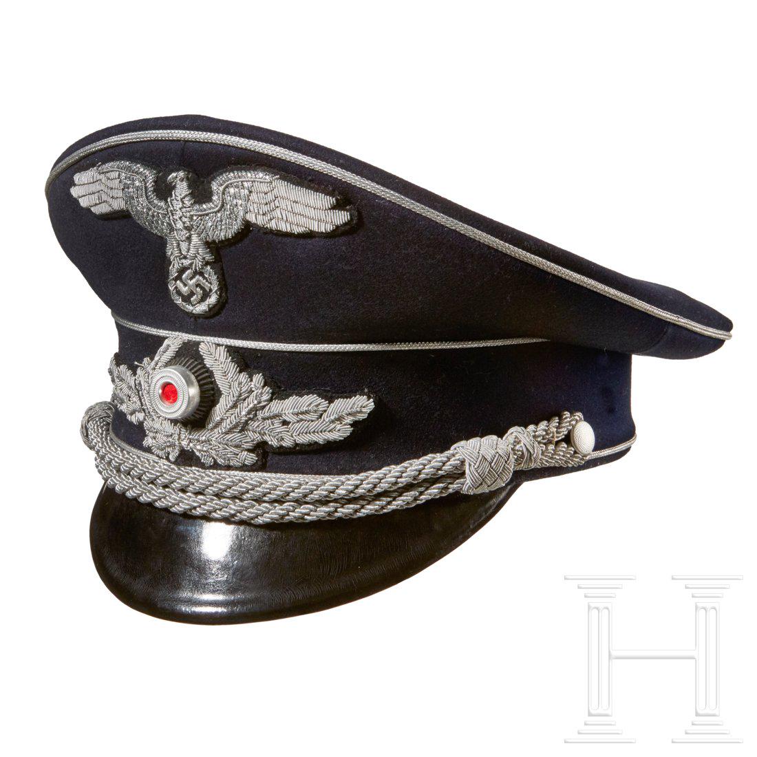 A Visor Cap for Diplomatic Officials: Dark blue doeskin, dark blue wool center band, silver piping and silver-aluminum braided chin cords, retained by pebbled button attachment. Black lacquered visor, checkered tan underside. Gold rayon l