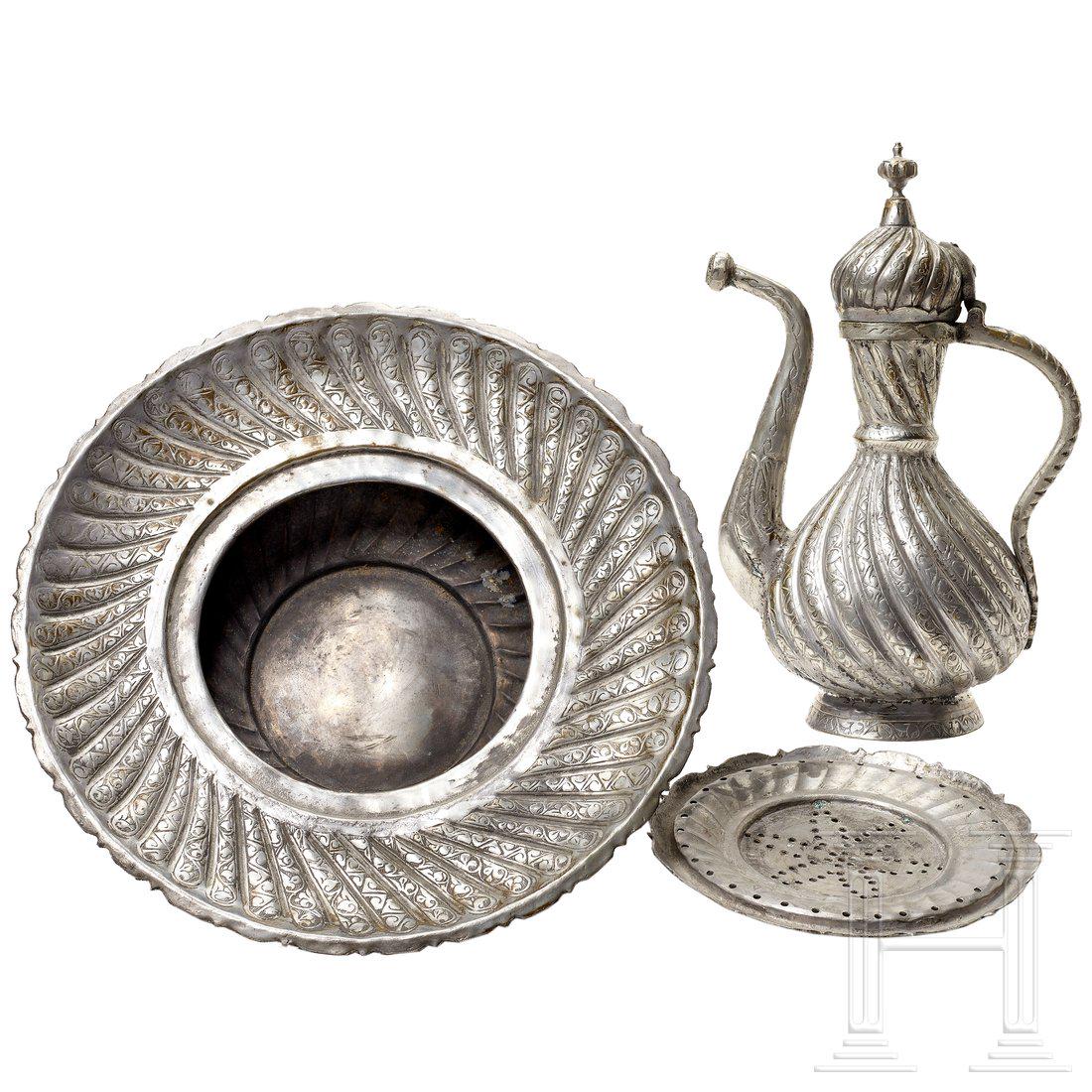 An Ottoman washing set, circa 1900: An Ottoman washing set, circa 1900Verzinntes Messing. Segmentiert fein getriebener, bauchiger Korpus mit eingesetztem Boden und S-fÃ¶rmigem Ausguss. Die OberflÃ¤che floral und geometrisch graviert