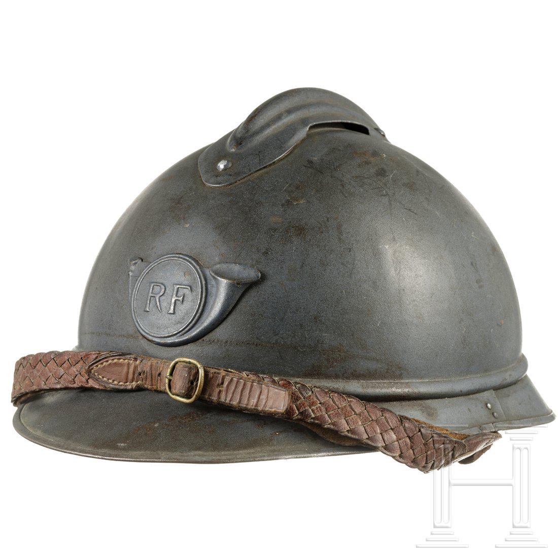 A French steel helmet M 15 Adrian for Chasseurs, circa: A French steel helmet M 15 Adrian for Chasseurs, circa 1915 - 1918Stahl, blaugrau lackiert (berieben, leichte Dellen), angenieteter Kamm, stirnseitig aufgelegtes Hornsymbol "RF". Schwarzes Lederlasche