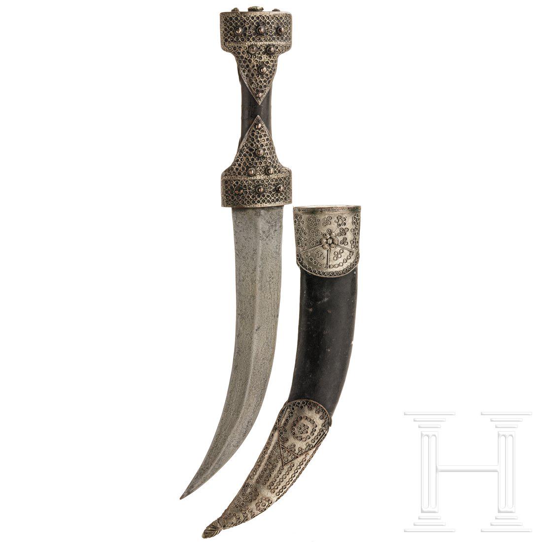 A Kurdish khandjar, 19th century: A Kurdish khandjar, 19th centuryGeschwungene, gegratete Damastklinge, hÃ¶lzerner Griff mit filigranverzierter Silbermontierung. Belederte Scheide mit en suite verzierten BeschlÃ¤gen. LÃ¤nge 41 c