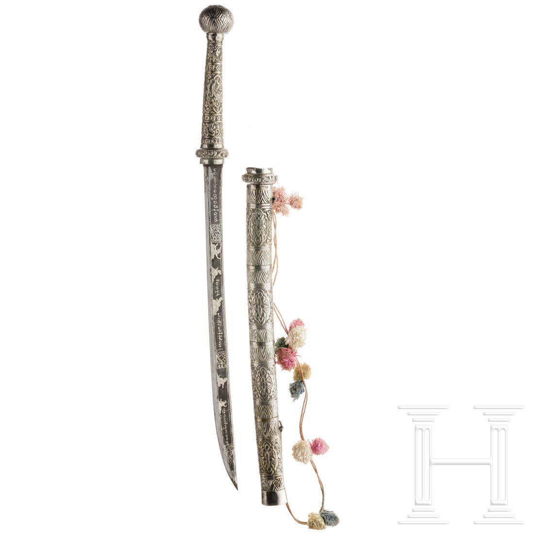 A Burmese dha, 19th century: A Burmese dha, 19th centuryKrÃ¤ftige, leicht gekrÃ¼mmte RÃ¼ckenklinge mit figÃ¼rlichem und ornamentalem Dekor in Silber-Tausia. GefÃ¤ÃŸ aus getriebenem und versilbertem Messing. Scheide au