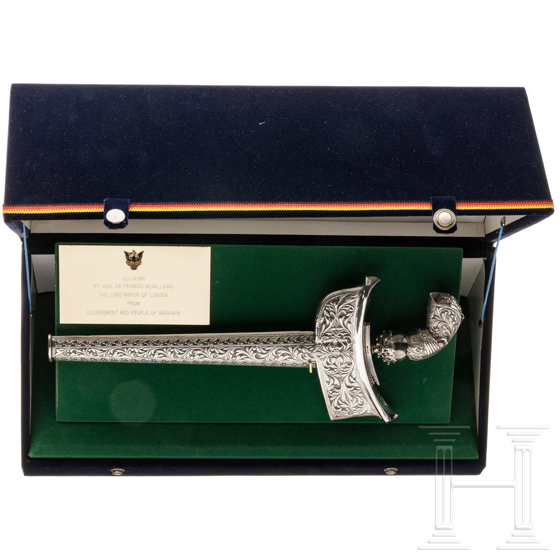 A presentation keris from Borneo, 20th century: A presentation keris from Borneo, 20th centuryVernickelte, geflammte Klinge, reliefierter Griff, floral getriebene Scheide. LÃ¤nge 40 cm. In mit grÃ¼nem Textil ausgeschlagener PrÃ¤sentationskass