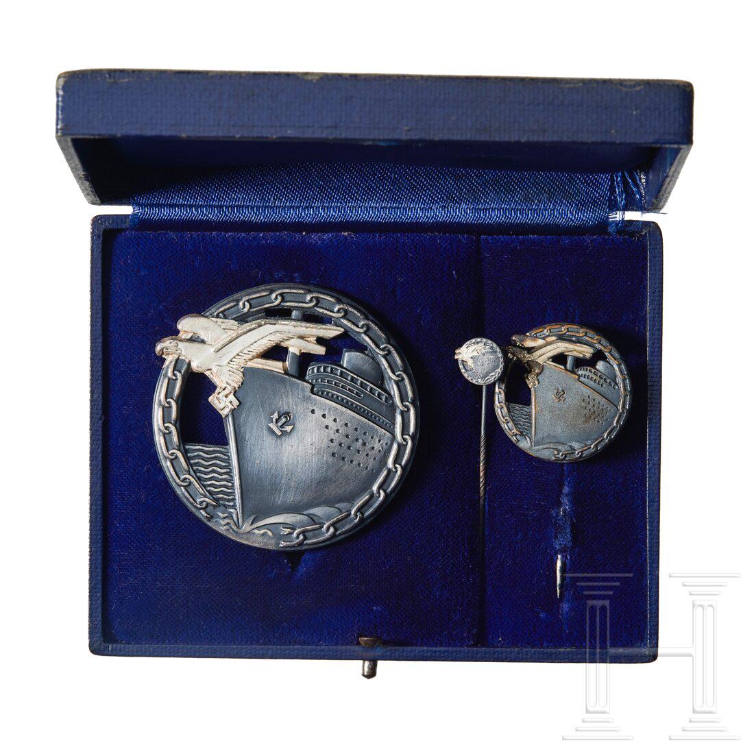 A Cased Set of Blockade Runner Badges: A Cased Set of Blockade Runner Badges Die struck patinated and silvered tombac badges, consisting of a large badge with its matching issue stick pin, reverse with vertical pin, barrel hinge and a flat