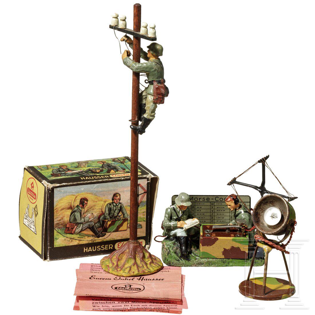 A Hausser Elastolin Morse Code Group 0/659/8 in: A Hausser Elastolin Morse Code Group 0/659/8 in original box with description, a soldier working on a telephone pole and a search lightHausser-Elastolin, Blech-Masseausführung, 7 cm-Serie, 30er Jahre