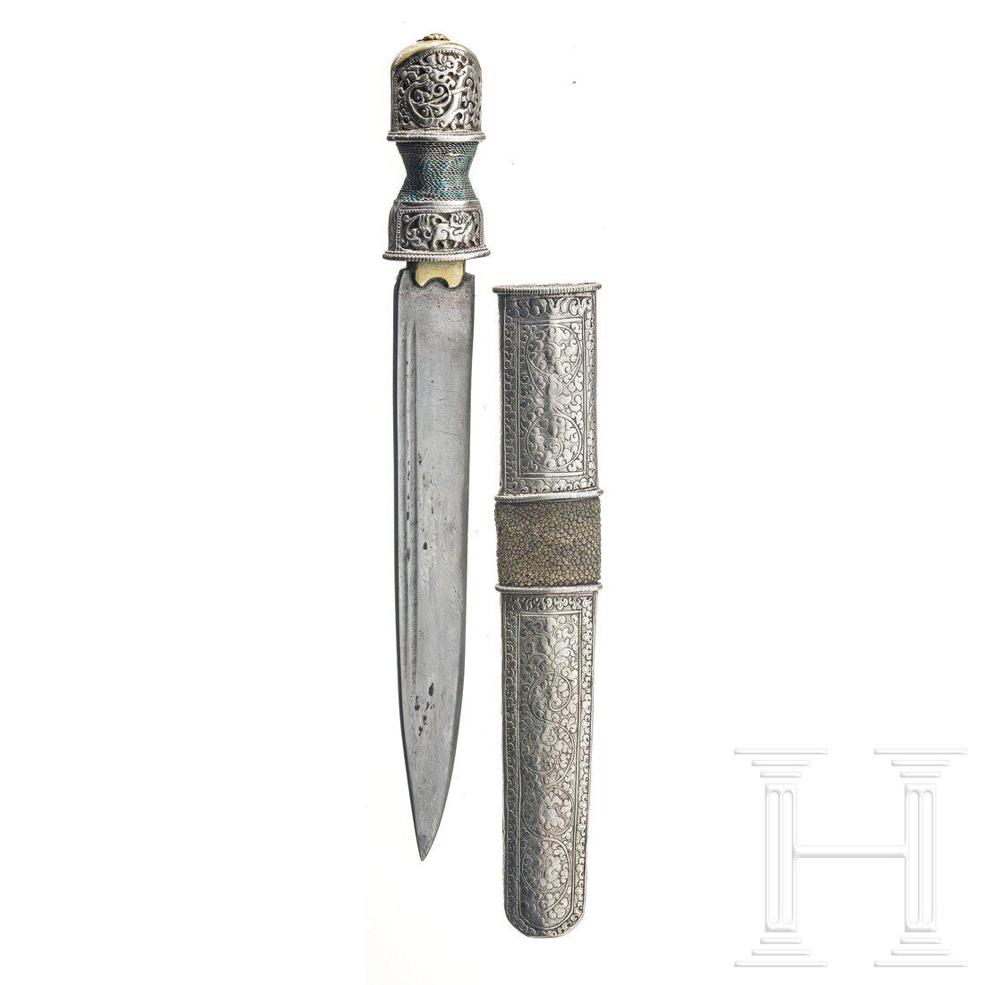 A Tibetan silver-mounted dughti, 19th century: A Tibetan silver-mounted dughti, 19th century Kräftige, spitz zulaufende Keilklinge, beidseitig mit zwei Zügen, Griff mit reliefierter Hilze aus Silber und Drahtwicklung, Knaufkappe aus Mess