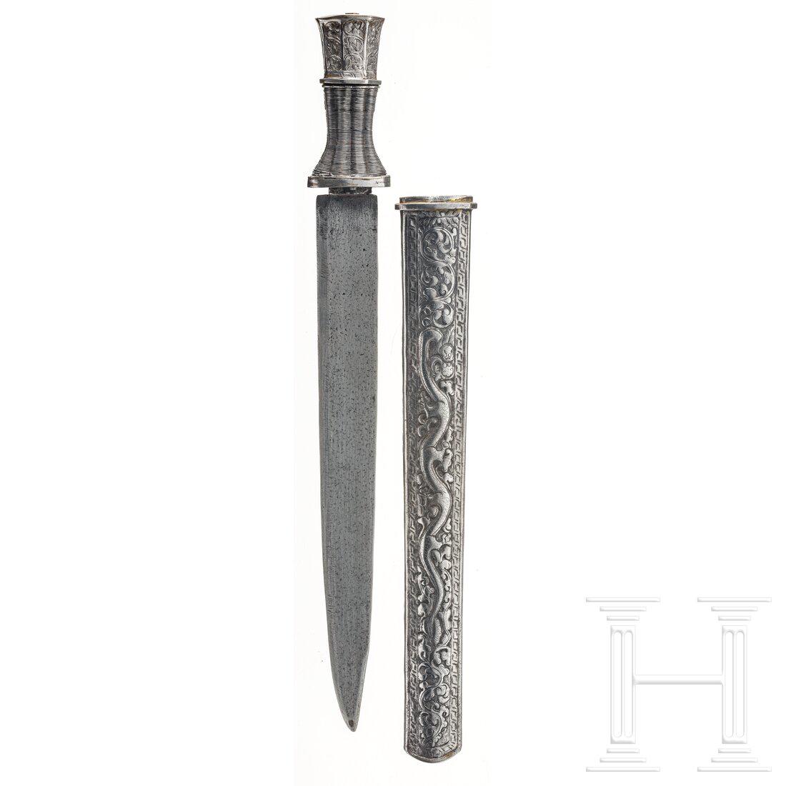 A large Tibetan dughti, circa 1900: A large Tibetan dughti, circa 1900 Kräftige Rückenklinge, Hilze mit Drahtwicklung und gravierter Knauf. Eiserne, figürlich getriebene und gravierte Scheide. Länge 47 cm. Condition: