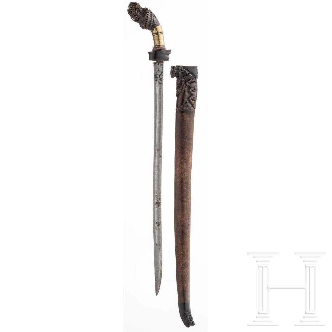 A Malayan golok, 19th century: A Malayan golok, 19th century Gekehlte Rückenklinge, gereinigt und stellenweise narbig. Parierstange aus Horn und Griffzwinge aus Messing. Fein beschnitzter und stellenweise beschnitzter Knauf, e