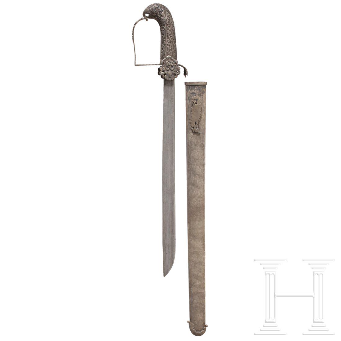 A Malaysian Mandau, 19th century: A Malaysian Mandau, 19th century Straight single-edged blade made from bog iron ore. Finely chased and chiselled silver hilt, the pommel shaped like a bird's head. The scabbard coated with silver and 