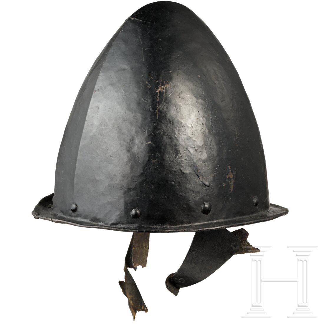 A Flemish musketeer's helmet, circa 1600/10: A Flemish musketeer's helmet, circa 1600/10 Einteilig geschlagene, geschwärzte Kalotte mit leichter mittiger Gratung. Schmale umlaufende Krempe mit gebördeltem Rand. Seitlich verbeult, an ei