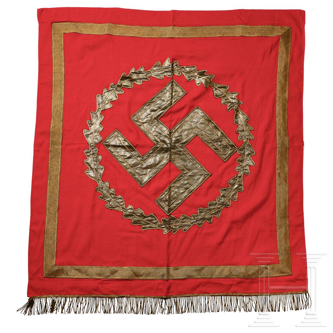 An NSDAP Podium-Wall banner: An NSDAP Podium-Wall bannerSingle-sided, red cotton cloth, bottom edge trimmed in gold metallic fringe, top with stitched sleeve for pole suspension. Gold brocade border frame around four sides, at th