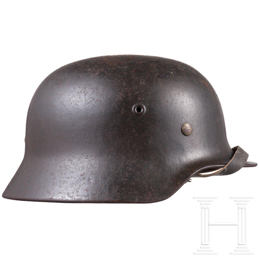 An air force steel helmet M 40 with a single decal: An air force steel helmet M 40 with a single decalDie Glocke mit mitgeprÃ¤gten BelÃ¼ftungsnieten und Resten der luftwaffenblauen Lackierung (flugrostig, konserviert), das Adlerabzeichen zu ca. 90 