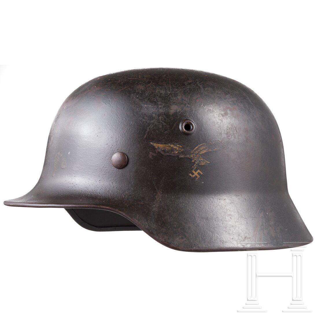 An air force steel helmet M 40 with a single decal: An air force steel helmet M 40 with a single decalDie Glocke mit mitgeprÃ¤gten BelÃ¼ftungsnieten und Resten der luftwaffenblauen Lackierung (flugrostig, konserviert), das Adlerabzeichen zu ca. 50 