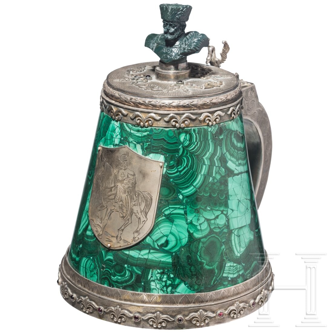 A Russian silver and malachite tankard: A Russian silver and malachite tankardSilver, the interior gilt. Conically tapering body in a malachite casing. An appliquéd silver plaque with engraved horseman on the front. The hinged lid with a g