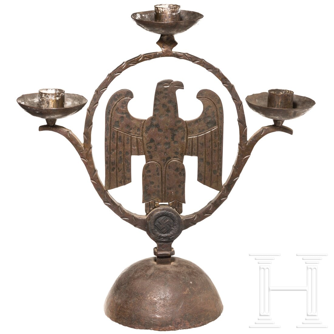 A candleholder: A candleholderSchmiedeeisen, geschwärzt. Im kreisförmigen Zentrum ein Adler auf Hakenkreuz. Angeschraubter Standfuß aus halbkugelförmiger Schale. Gebrauchs- und Altersspuren. Höhe 44 cm.Condition