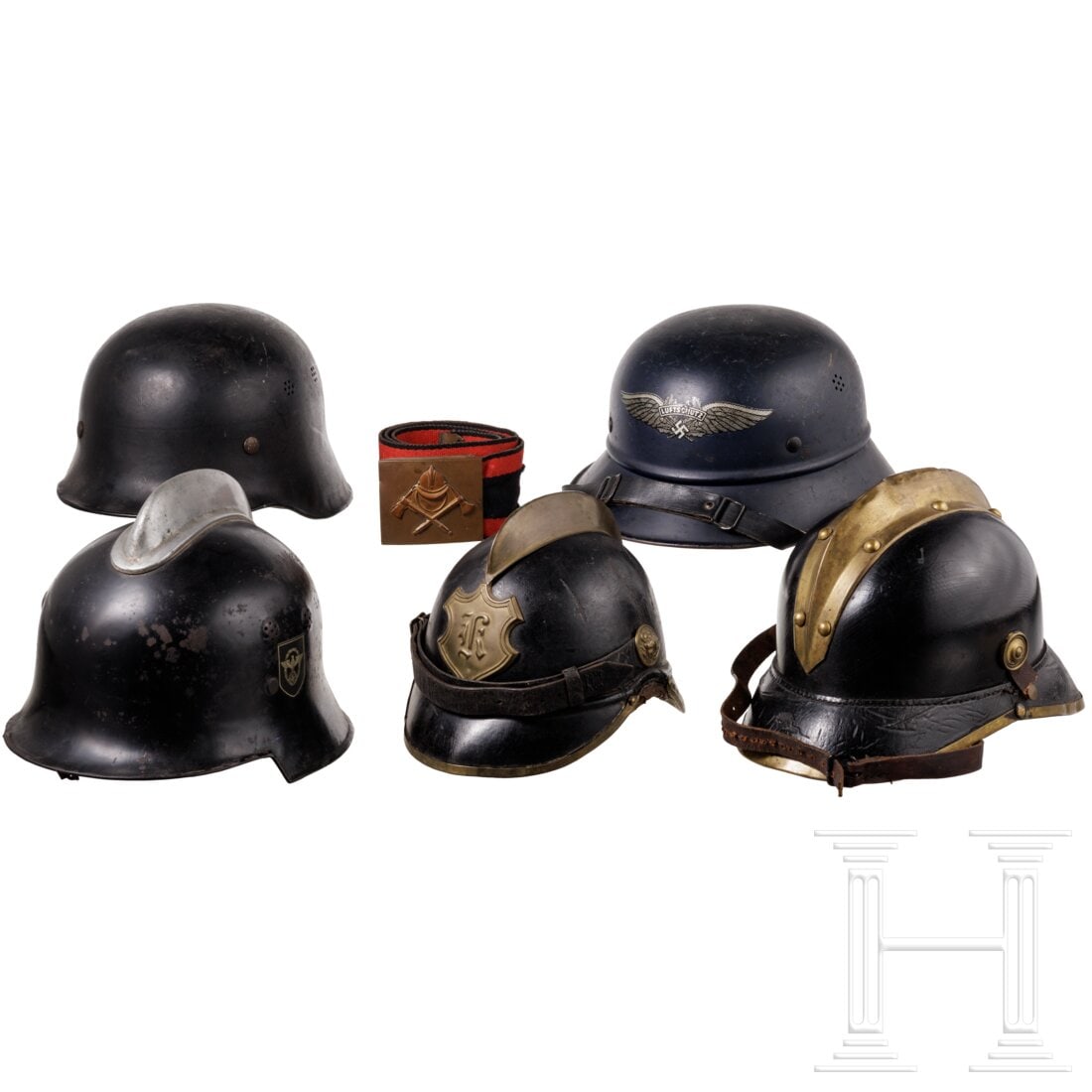 A small group of fire department helmets: A small group of fire department helmetsZwei Lederhelme mit Messingbeschlägen und -kamm, bei einem ist der Kinnriemen gerissen. Ein schwarz lackierter Stahlhelm mit Aluminiumkamm und beiden Abzechen,