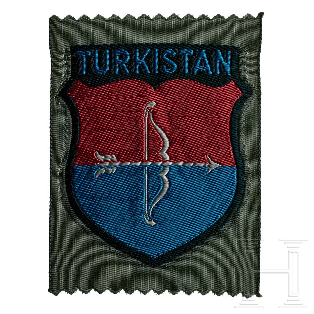 An Arm Shield for Turkistan Volunteers: An Arm Shield for Turkistan VolunteersField-grey rayon base, machine-woven red/blue shield, white bow and arrow at centre, blue lettering in banner at top "TURKISTAN". USA lot - more info hereConditio
