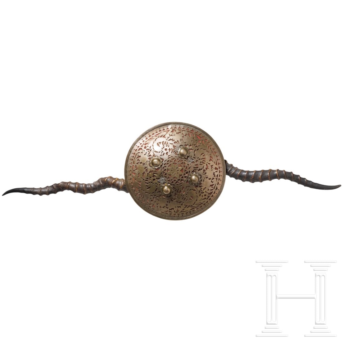 An Indian buckler (madu), 20th century: An Indian buckler (madu), 20th centuryKräftig gewölbter Schild aus zweilagigem Messingblech, die obere Lage floral durchbrochen und mit rotem Textil hinterlegt. Vier Schildbuckel. Seitlich zwei Anti