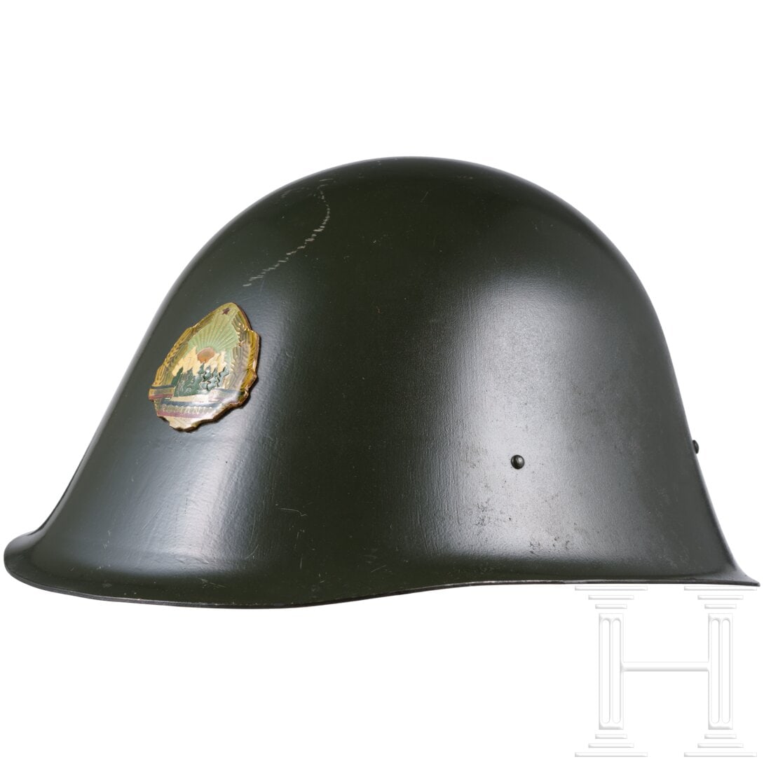 A Romanian M73/80 steel helmet with parade badge: A Romanian M73/80 steel helmet with parade badgeGrün lackierte Helmglocke mit Paradeabzeichen auf der Vorderseite. Am Rand (hinten) gestempelt "420929" und "85-019". Komplett mit Innenfutter und Kinn