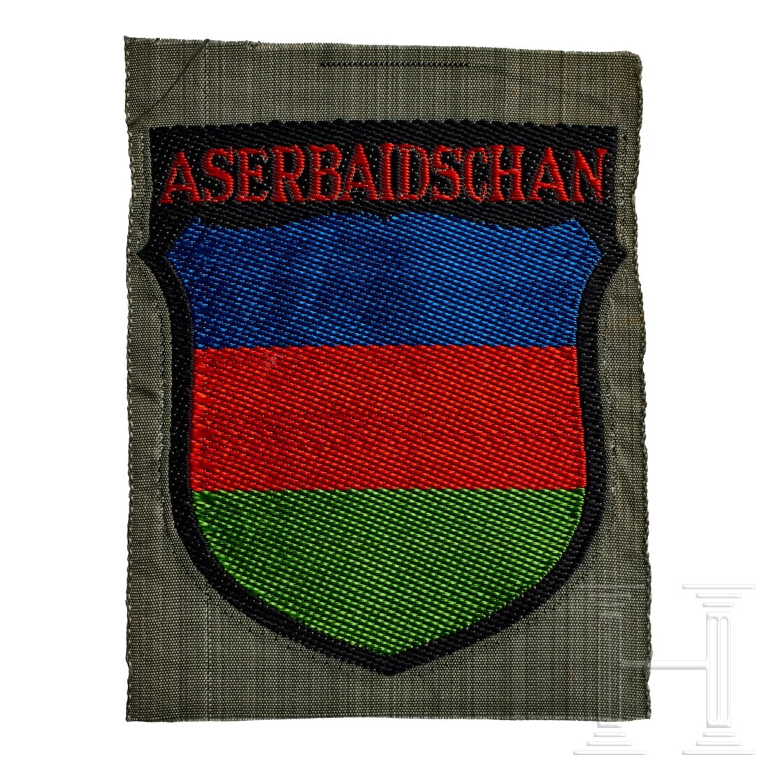 An Arm Shield for Azerbaidjani, First Pattern 1942-43: An Arm Shield for Azerbaidjani, First Pattern 1942-43Field-grey rayon base, machine-woven shield of blue/red/green horizontal segments outlined in black, "ASERBAIDSCHAN" in red lettering at top.USA lo