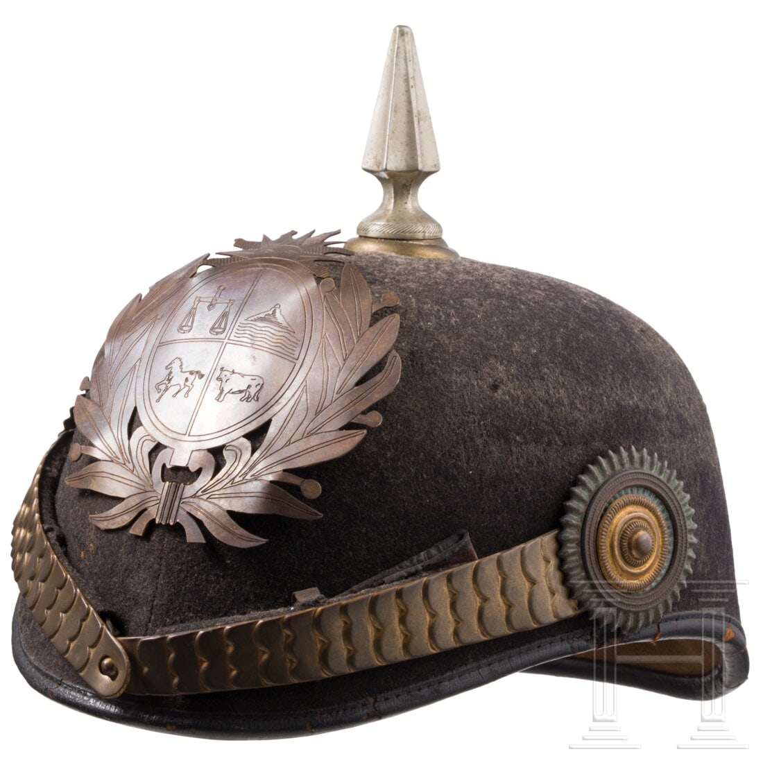 Uruguay - A helmet for members of the police, circa 1930: Uruguay - A helmet for members of the police, circa 1930Korpus aus steifem korkartigen Material (Druckstellen) mit Metallbeschlägen. Bezug aus schwarzem Tuch. Schauseitig aufgelegt das Emblem mit Wap