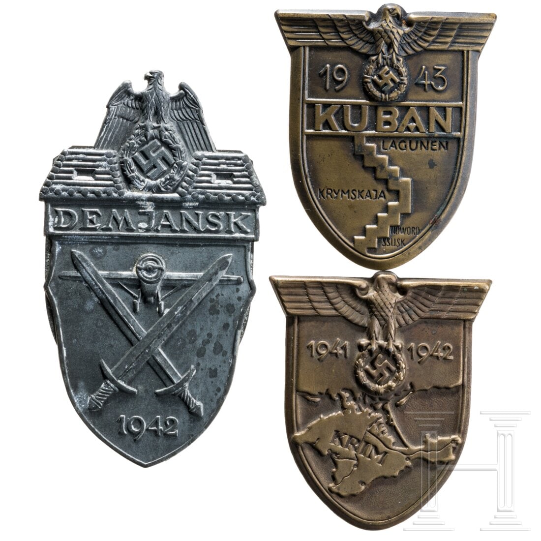Three arm shields: Three arm shieldsKuban- und Krimschild (Splinte fehlen) in bronzierter Eisenausführung, jeweils ohne Stoffunterlage und Gegenplatte. Demjanskschild in Feinzinkausführung, fleckig, nicht stimmige Geg