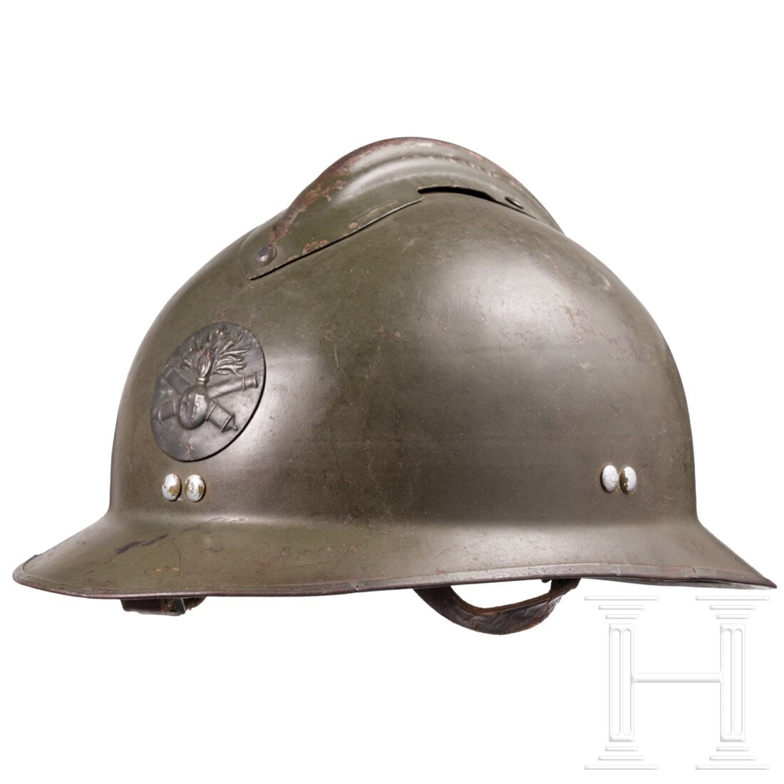 A M 26 “Adrian?? helmet for artillery: A M 26 “Adrian” helmet for artilleryOlivbraun lackierte Metallglocke mit mitgeprägtem Rand (eiserne Einfassung), vernieteter eiserner Verstärkungskamm (bestoßen) und vs. aufgelegtes rundes 