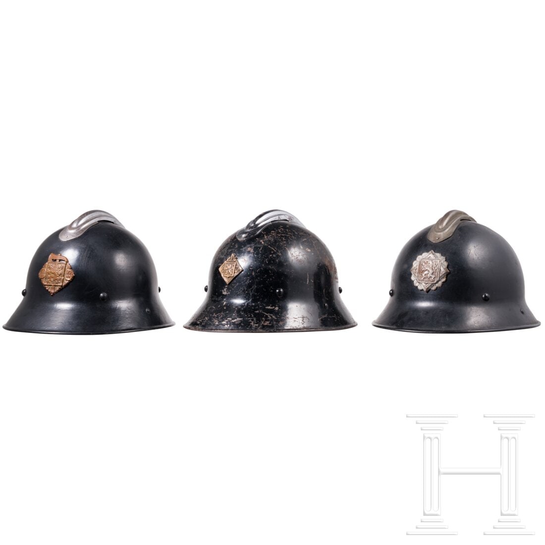 Three firefighters' helmets: Three firefighters' helmetsJeweils schwarz lackierte Eisenglocken mit vernickeltem/blank Kamm und vs. aufgelegtem Emblem. Komplett mit Innenfutter.Condition: II - III