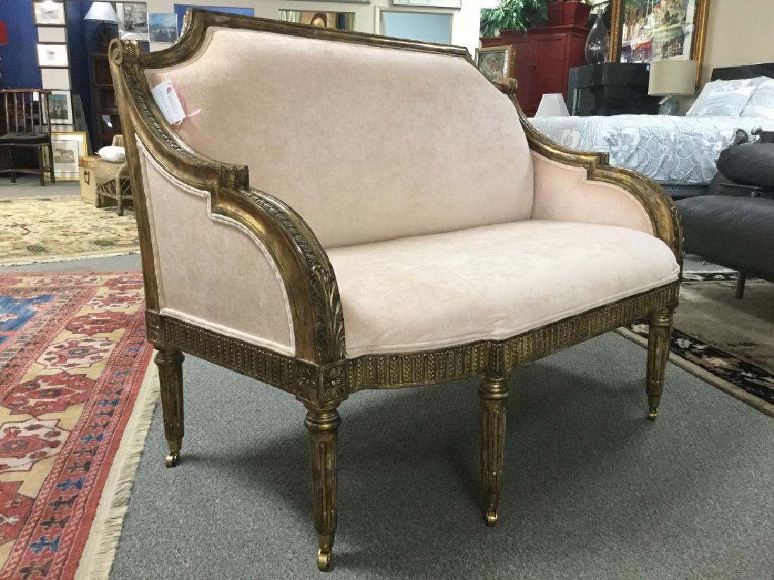 Maitland Smith Velvet Setee: This Maitland-Smith sette features carved scroll and rope detailing with gilded acanthus leaf highlights that accent fluted legs on casters. The seat fabric consists of a soft pink velvet. Measuring 3
