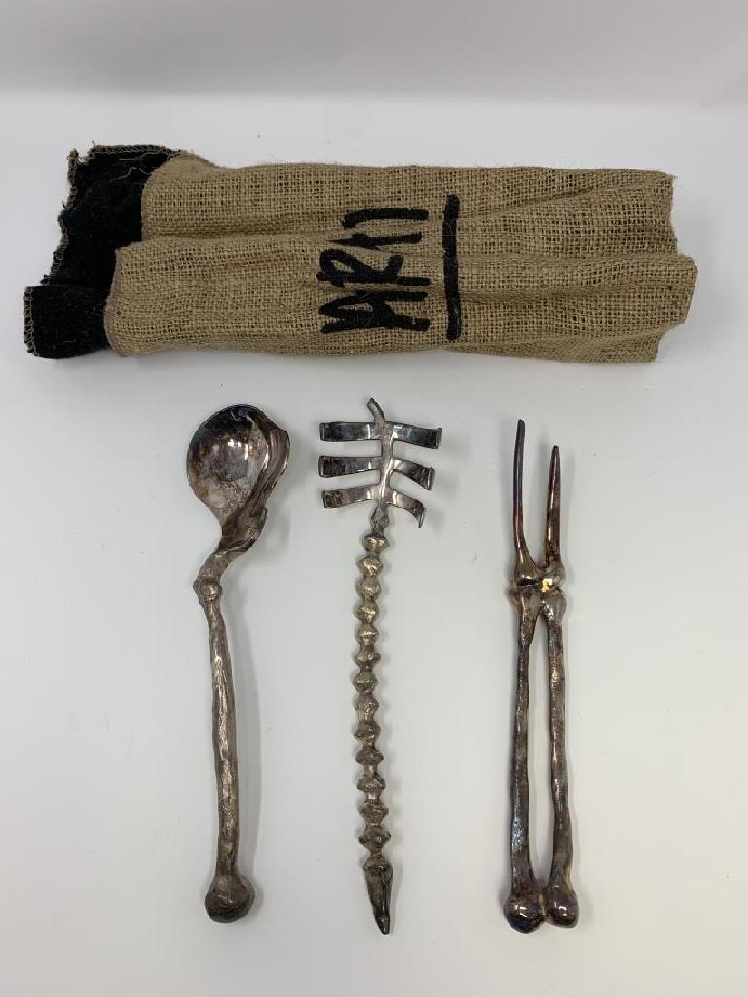 MICHAEL ARAM "BONE" SILVERPLATE SKELETON UTENSILS: A three-piece silver plate serving utensil set in the Bone pattern, designed by Michael Aram. This set includes a meat serving fork and a two-piece salad serving set comprised of a salad fork and spoo