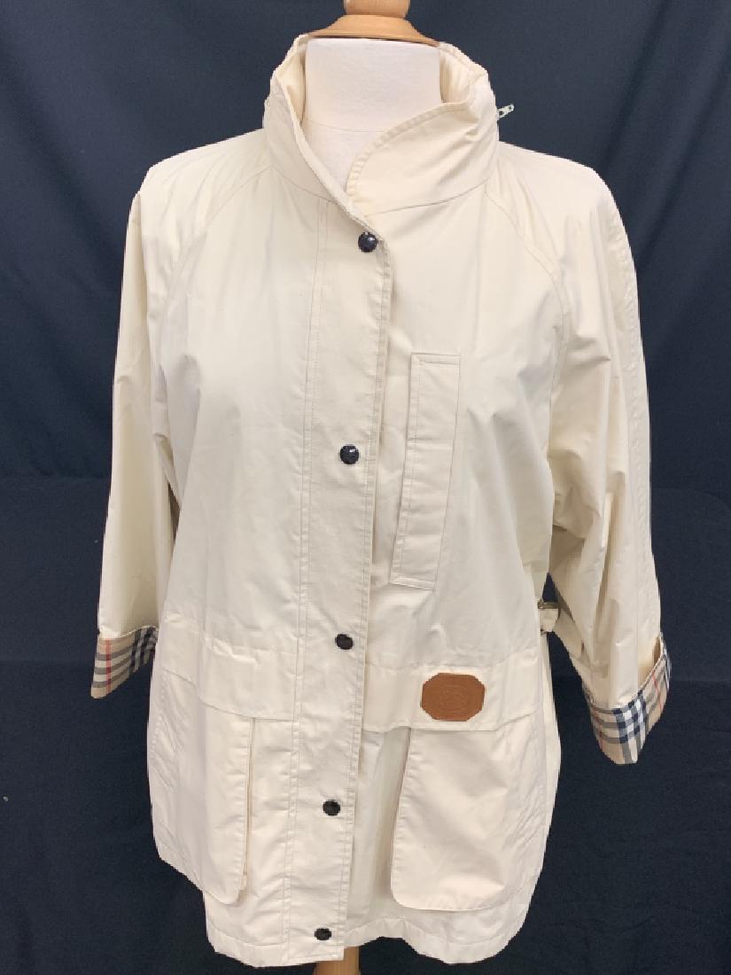 BURBERRY CLASSIC STYLE WINDBREAKER WOMANS MED: BURBERRY CLASSIC STYLE WINDBREAKER WOMANS MED Classic style windbreaker by BURBERRY. Size Medium.Zipper and button up front. 2 top/side pockets on exterior. Hide-a-way hood in collar.Made with a 50/50