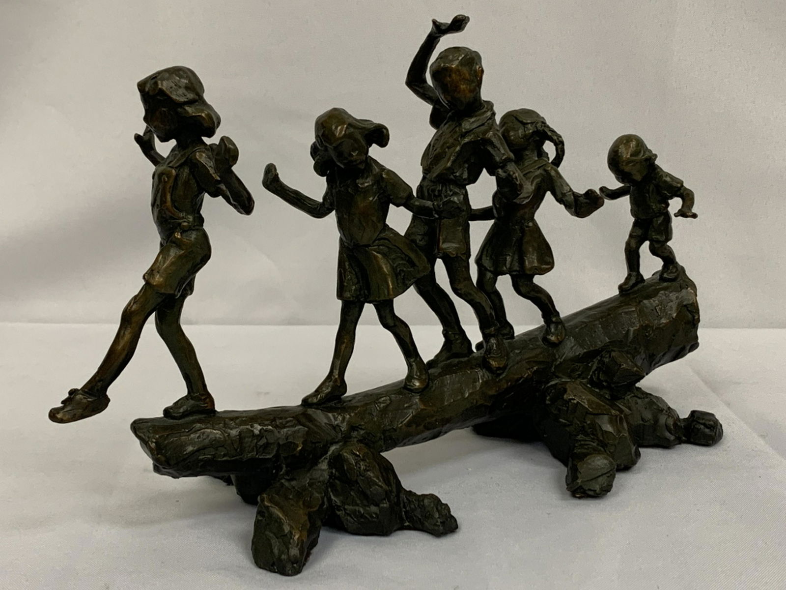 JANE DEDECKER CHILDREN ON A LOG "SHORTCUT" BRONZE: Bronze sculpture of a line of children tip toe-ing across a log. Entitled "Shortcut" and designed by artist Jane DeDecker. Signed on bronze. Measures 13.5" x 5.5" x 9" in size. Excellent condition! Th