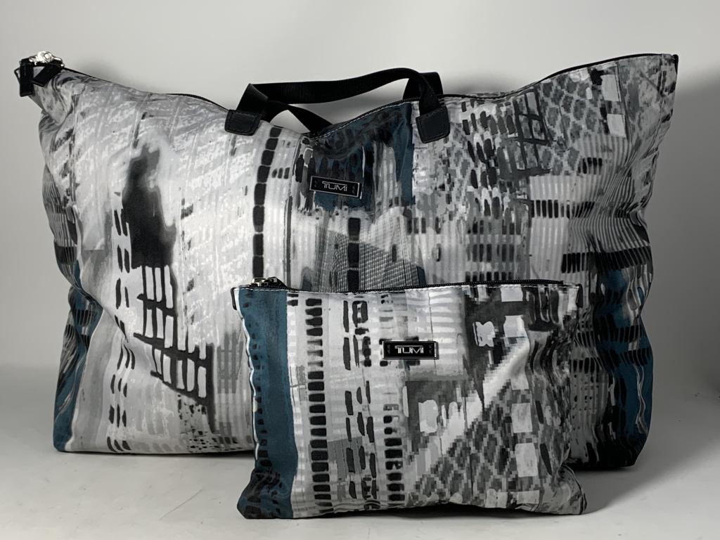 LARGE TUMI TOTE VOYAGER B&W CITY W/COSMETIC BAG: Measures 22" across and 13" tall. Double handled with logo on outside. Very good condition. Comes with cosmetic purse. Third party shipping required