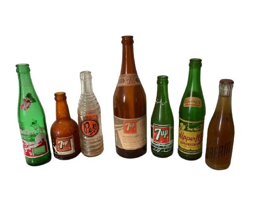 LOT OF 7 VINTAGE MID CENTURY SODA POP BOTTLES: LOT OF 7 RARE VINTAGE MID CENTURY COLLECTIBLE SODA POP BOTTLES INCLUDING MOUNTAIN DEW 7UP PEP UPPER 10 AND DREAM -WEAR CONSISTENT WITH AGE -B122 DP12120