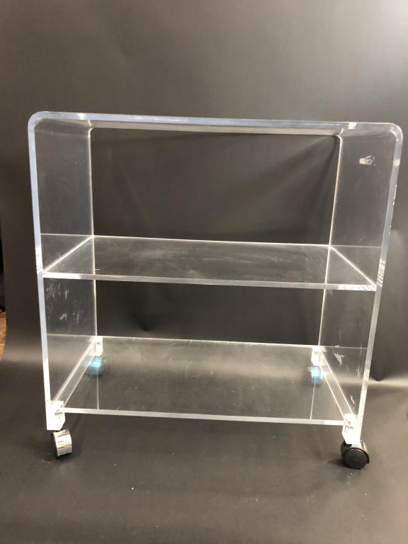 MID MOD LUCITE BAR CART 30": MID CENTURY MODERN LUCITE BAR CART HOME DECOR -30" X 27" X 15.5" APPROX -VERY GOOD CONDITION, MINOR SURFACE SCRATCHES, CLEANABLE MARKS / RESIDUE TO SURFACE -BACK WHEELS STILL MAINTAIN BLUE FACTORY PLA