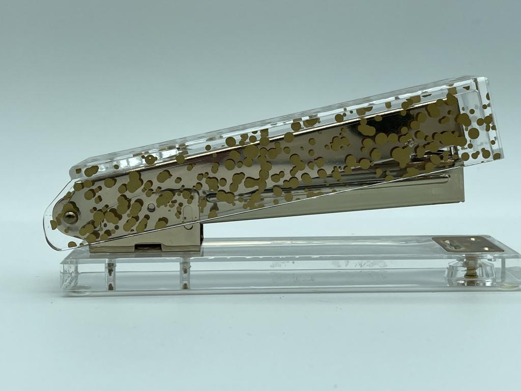 GOLD FLECK AND LUCITE STYLE STAPLER 5": POSTMODERN DESIGN GOLD FLECK AND LUCITE STYLE STAPLER | LUXURY HOME OFFICE WORK TABLE ACCESSORIES -3" X 6" X 1.5" APPROX - VERY GOOD CONDITION CONSISTENT WITH AGE, WEAR CONSISTENT WITH AGE, SEE PHOTOS
