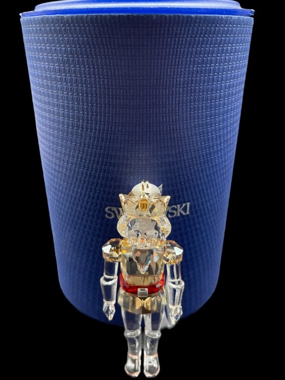 SWAROVSKI NUTCRACKER ORNAMENT: A timeless decoration with a festive color combination. Hanging on a white satin ribbon, Swarovski's Nutcracker Ornament is beautifully crafted in clear, golden and red crystal. It makes an elegant ad