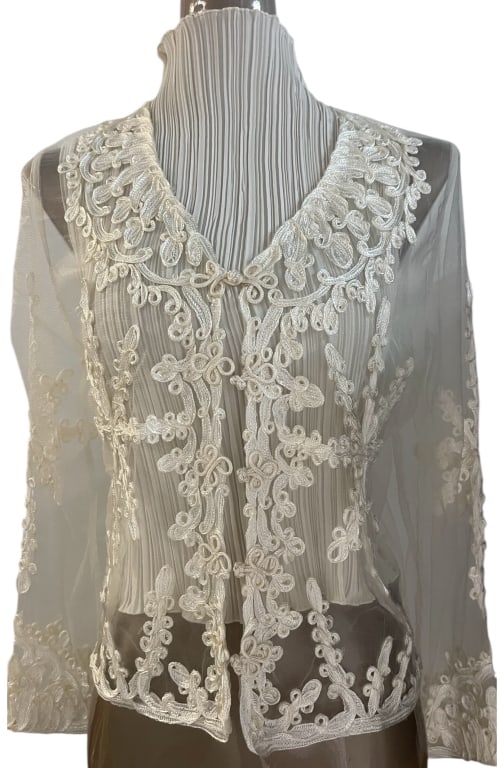 KNOT KNOTS EMBROIDERED SHEER TOP: KNOT KNOTS EMBROIDERED SHEER TOP THIS ELEGANT AND INTRICATE SHEER TOP BY KNOT KNOTS FEATURES DELICATE FLORAL EMBROIDERY AND AN AIRY, LIGHTWEIGHT DESIGN. THE V-NECKLINE IS ADORNED WITH ORNATE EMBROIDER