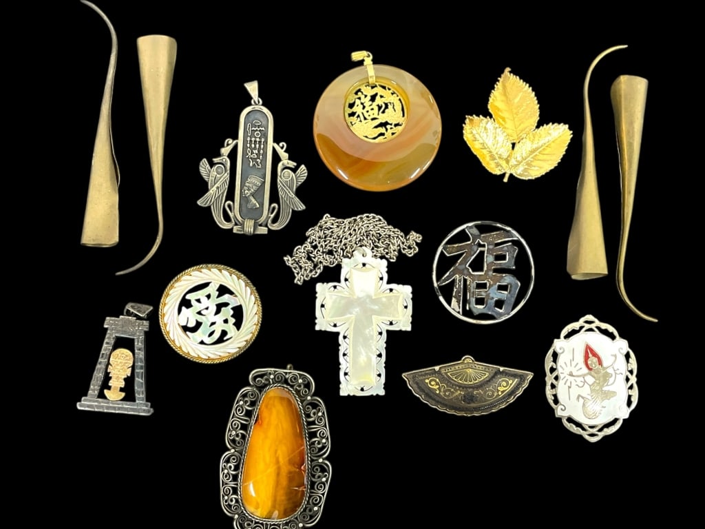 COLLECTION OF VINTAGE & ANTIQUE ASIAN JEWELRY: COLLECTION OF VINTAGE AND ANTIQUE ASIAN-INSPIRED JEWELRY & ACCESSORIES. INCLUDES CARVED AGATE AND MOTHER-OF-PEARL PENDANTS, ORNATE SILVER AND GOLD-TONE BROOCHES, SYMBOLIC CHARMS, AND UNIQUE METAL FAN 