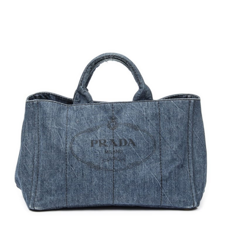 PRADA LARGE CANAPA TOTE BLUE DENIM CANVAS HANDBAG: A casual yet iconic staple from Prada, the Large Canapa Tote is crafted from durable blue denim canvas with tonal logo embroidery. This roomy tote features dual top handles, a structured silhouette, a