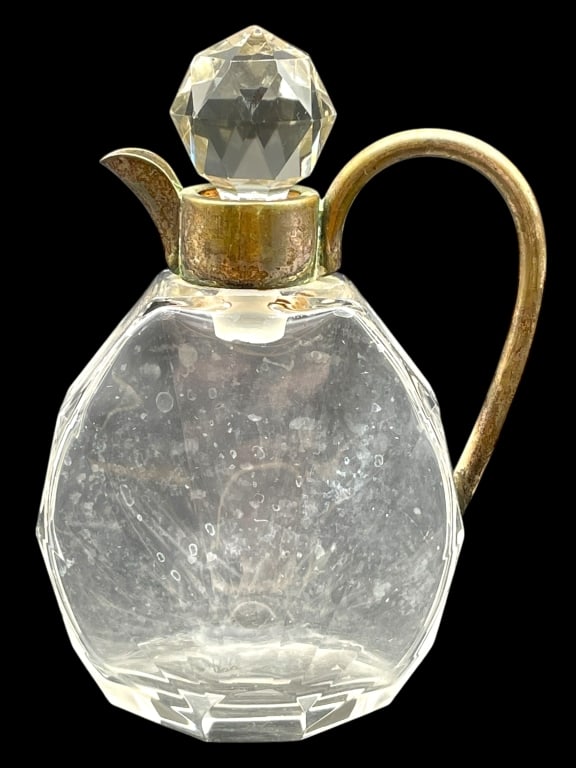 ART DECO CRYSTAL CARAFE W/ STOPPER 5": ART DECO CRYSTAL CARAFE W/ STOPPER 5" -VERY GOOD PRE OWNED CONDITION -APPROX 5" -FEATURES BRILLIANT MULTI-FACETED BODY, BRASS HANDLE, AND SPOUT. GEOMETRIC CRYSTAL STOPPER -JA 041525 By bidding on this