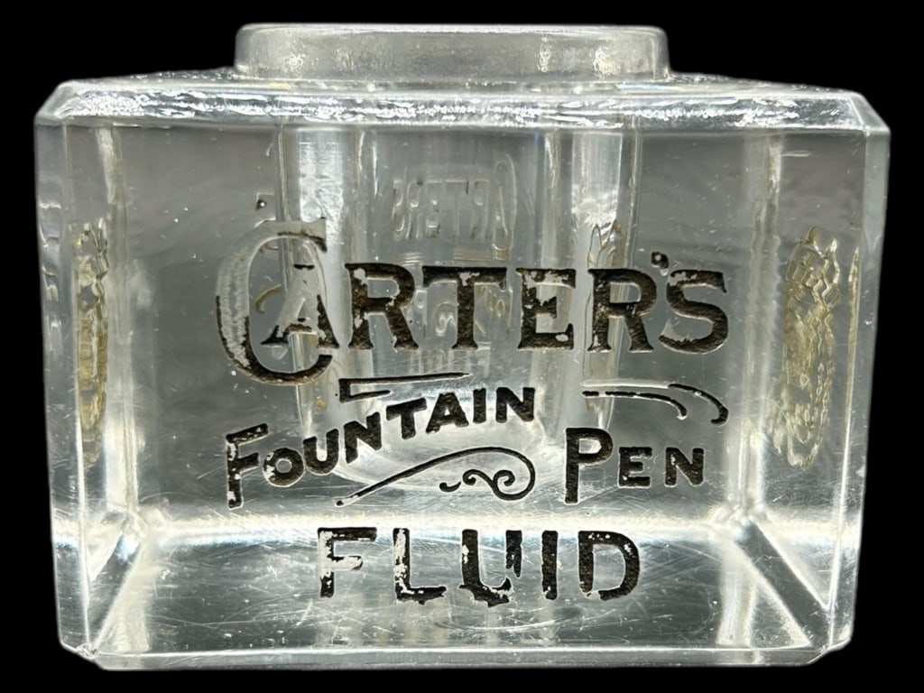 VINTAGE CARTER’S FOUNTAIN PEN FLUID INKWELL 3.5": - A CHARMING PIECE OF WRITING HISTORY, THIS HEAVY PRESSED GLASS INKWELL FEATURES BOLD BLACK GRAPHICS READING “CARTER’S FOUNTAIN PEN FLUID” ON ONE SIDE AND A CARTER’S INKS SEAL DESIGN ON TH