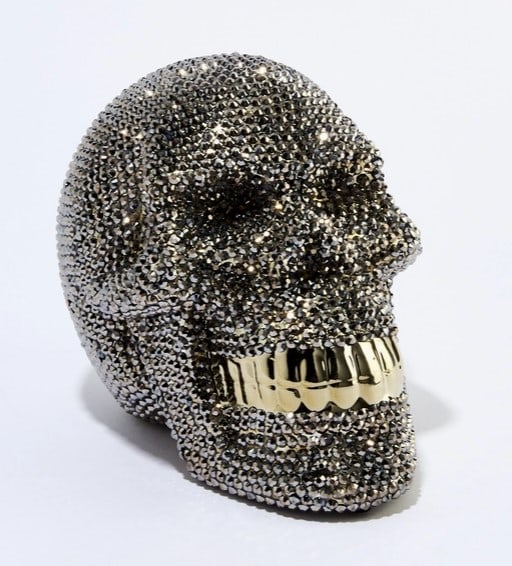 Rhinestone Skull Piggy Bank - 8" Long: Take some edge off with another classic concept with a simple, modern touch. A glossy grill rounds off this bold design. Stands 8" long. Features: - Felt pads - Removable coin plug Specifications: - I