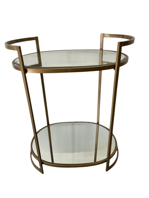 MODERN OVAL TWO-TIER GLASS AND METAL BAR TABLE: MODERN OVAL TWO-TIER GLASS AND METAL BAR TABLE WITH BRUSHED GOLD FINISH. FEATURES AN ELEGANT OVAL FRAME WITH CURVED HANDLES AND CLEAN LINES FOR A CONTEMPORARY SILHOUETTE. INCLUDES TWO CLEAR GLASS SHEL