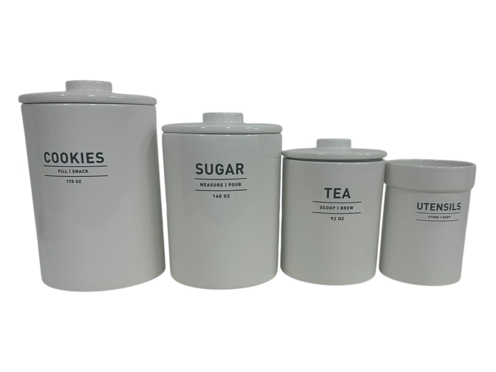 SET OF FOUR WHITE CERAMIC KITCHEN CANISTERS 12": - SET OF FOUR WHITE CERAMIC KITCHEN CANISTERS WITH TEXT LABELING – THIS MODERN SET INCLUDES CONTAINERS FOR COOKIES (170 OZ), SUGAR (140 OZ), TEA (92 OZ), AND UTENSILS, EACH STYLED WITH MINIMALIST BL